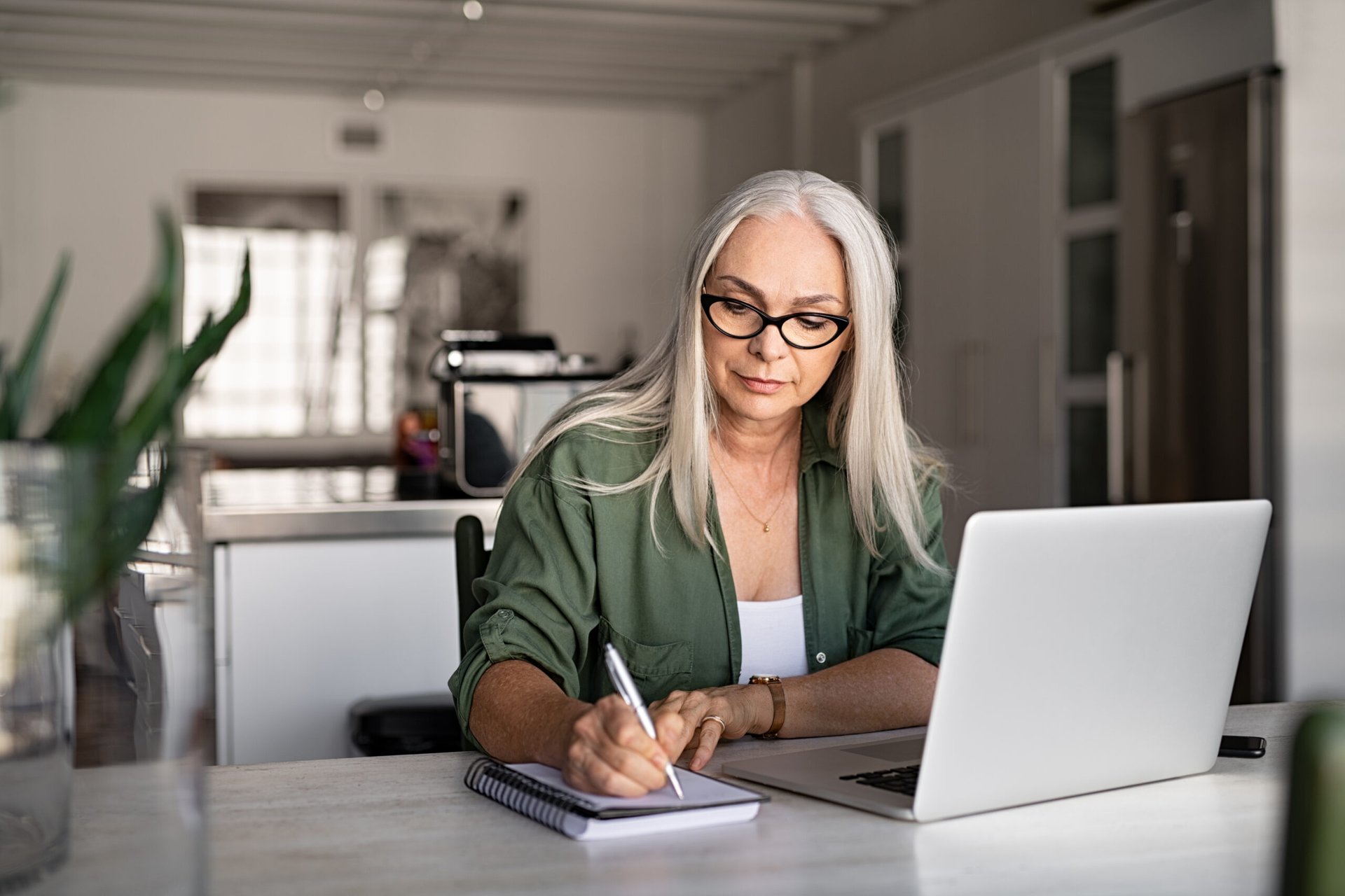 Woman with a computer and notepad at home