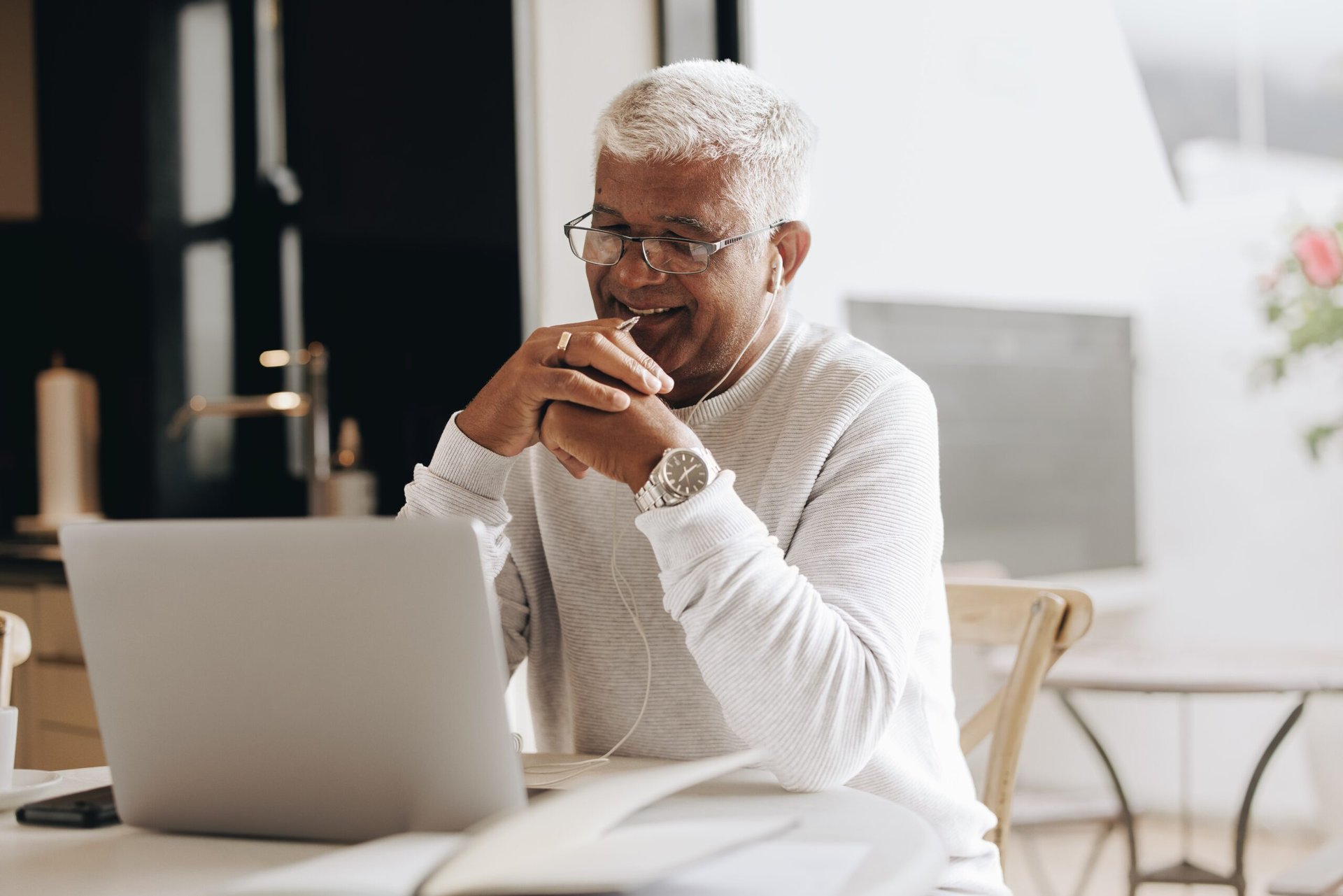 older man doing remote work at home in kitchen