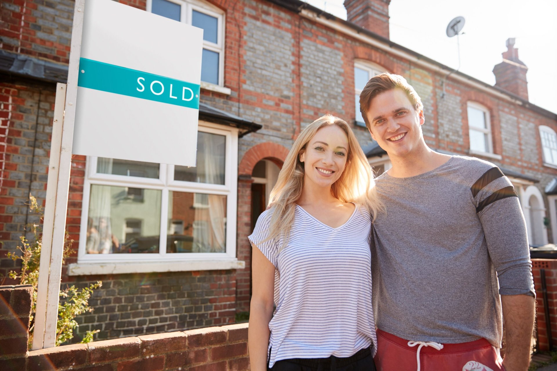 Happy homebuyer couple standing outside their new home