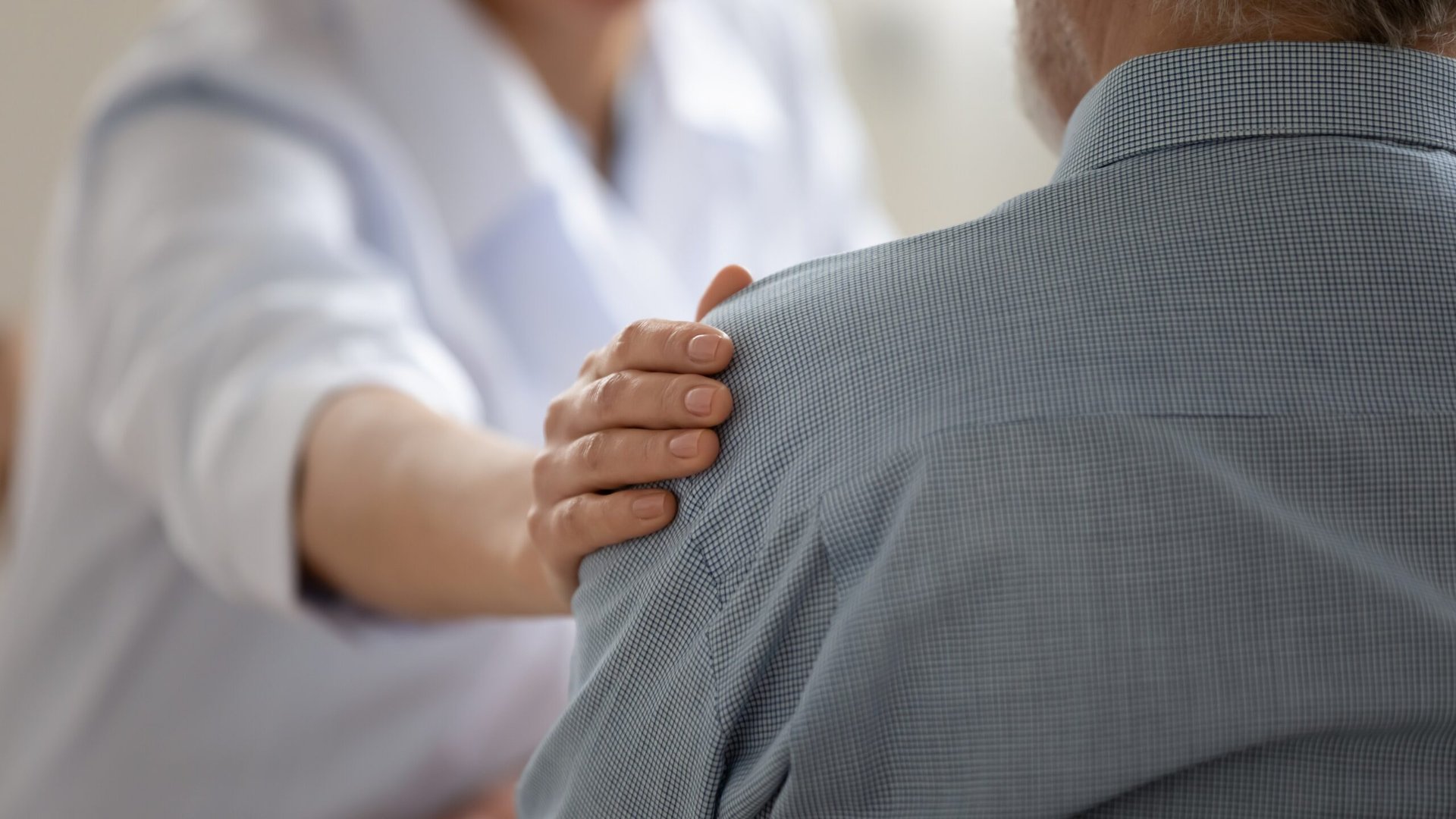 Someone comforting an older man struggling with mental health.