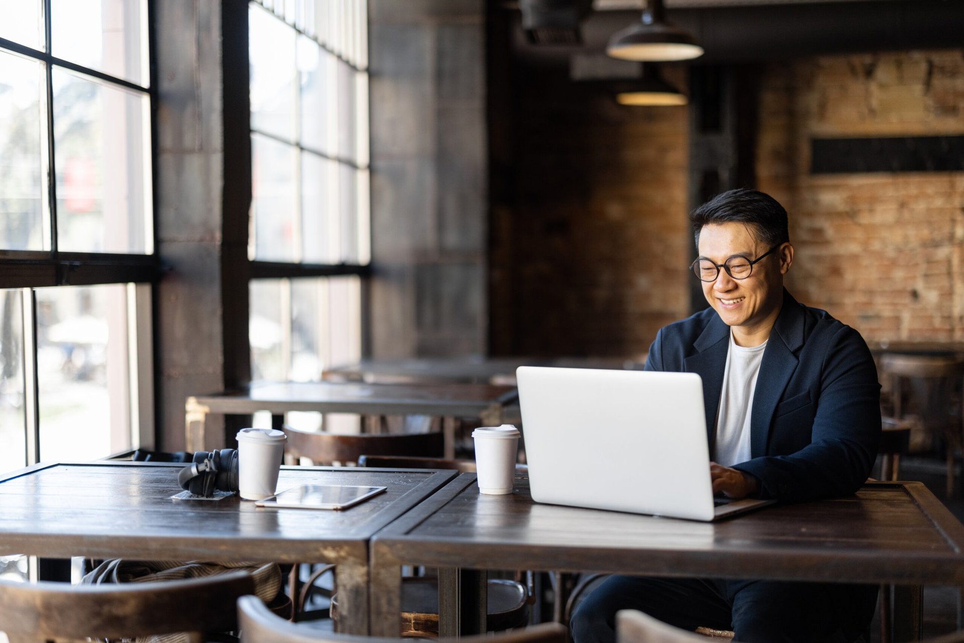 Smiling man works remotely in a cafe