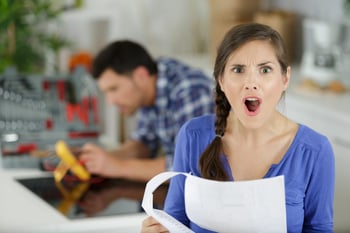 Surprised and frustrated woman homeowner looking at financial paperwork or invoicing for a repair bill or home maintenance costs
