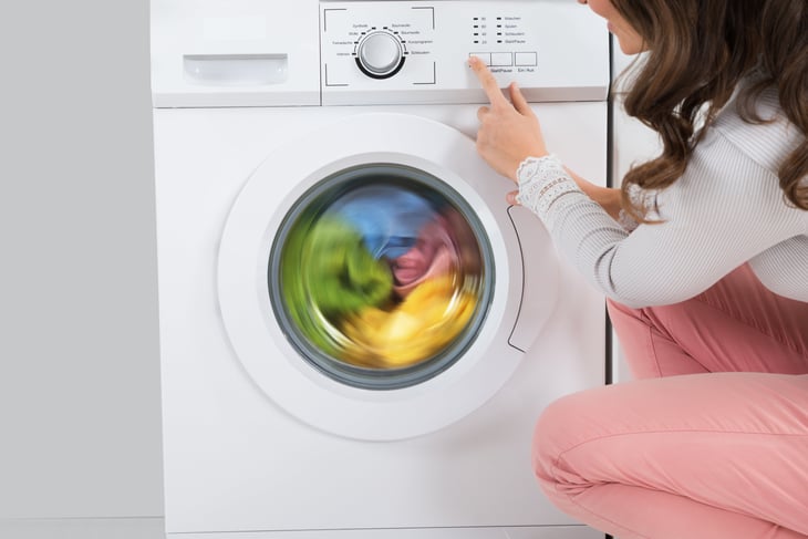 A woman uses a washing machine in her laundry room