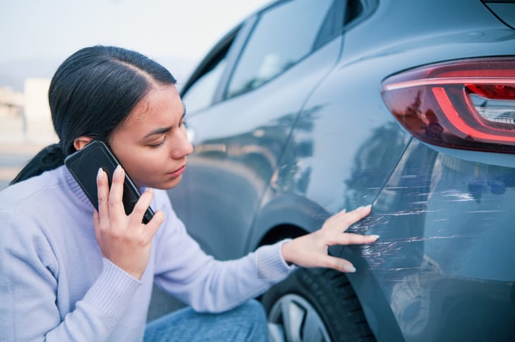 Woman calls insurance for scratched and damaged car.